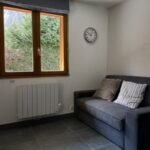Knusse woonkamer met groot raam en uitzicht op de natuur.