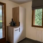 Knusse woonkamer met uitzicht op tuin en moderne keuken.
