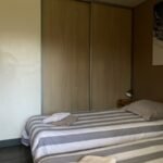 Comfortabele slaapkamer met gestreept beddengoed en grote kast.