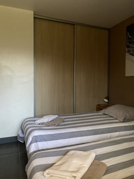 Comfortabele slaapkamer met gestreept beddengoed en grote kast.