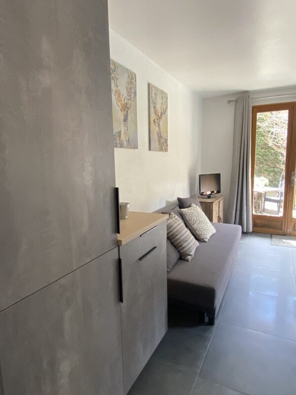 Gezellig interieur met bank, tv en uitzicht op tuin.