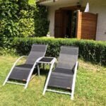 Tuin met twee ligstoelen en groene planten bij Chalet Carpe Diem.