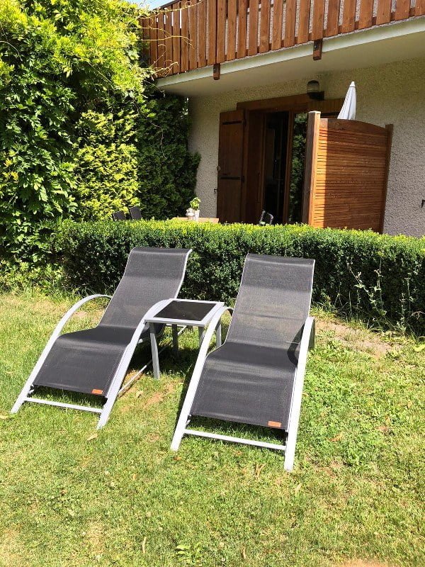 Tuin met twee ligstoelen en groene planten bij Chalet Carpe Diem.
