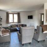 Gezellige woonkamer met comfortabele stoelen en tv in Chalet Carpe Diem.